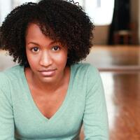 a headshot of a Black woman in her 30s wearing a light green sweater. 