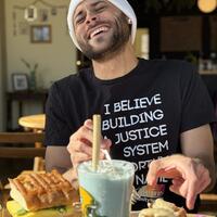 Man laughing in black shirt and white hat