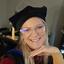 light skinned woman with glasses in commencement regalia